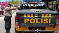 Seorang personil Polres Inhil menunjukkan mobil patroli yang dipasangi stiker imbauan penggunaan masker untuk mencegah penyebaran COVID-19. (Foto: Abdullah)