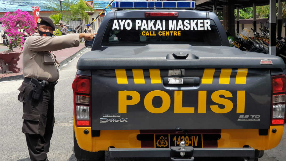 Seorang personil Polres Inhil menunjukkan mobil patroli yang dipasangi stiker imbauan penggunaan masker untuk mencegah penyebaran COVID-19. (Foto: Abdullah)