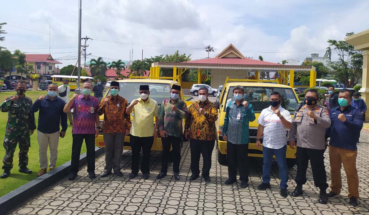 Berfoto bersama di depan dua mobil pick up bantuan dari program CSR Bank Riau Kepri. (foto: yra)
