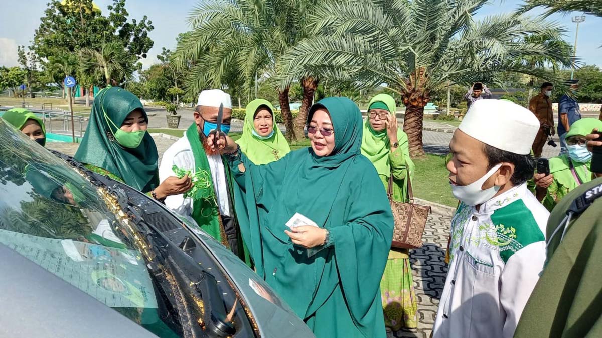 Ketua Muslimat NU Karimun menabur beras kunyit atau tepuk tepung tawar ke mobil mini bus bantuan dari Pemkab Karimun. (foto: yra)