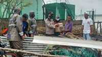 Kapolsek Buru Iptu Bakri menyerahkan bantuan kepada warga yang rumahnya rusak diterjang angin puting beliung. (foto: istimewa)