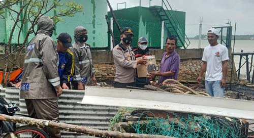 Kapolsek Buru Iptu Bakri menyerahkan bantuan kepada warga yang rumahnya rusak diterjang angin puting beliung. (foto: istimewa)