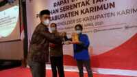 Komisioner KPU Karimun Syamsir menyerahkan penghargaan kepada IWO Karimun yang diterima ketuanya Rusdianto, terkait dukungan dan kerja sama dalam menyukseskan Pilkada Serentak 2020. (foto: istimewa)