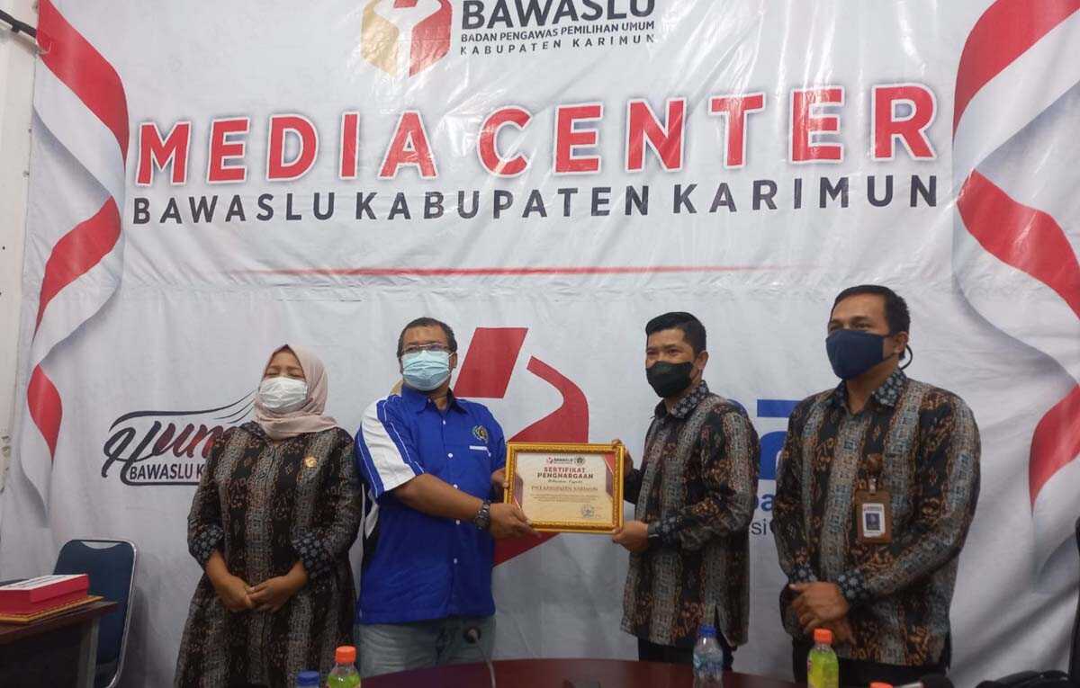 Ketua PWI Karimun Sandi Pramosinto menerima sertifikat penghargaan dari Ketua Bawaslu Karimun Nurhidayat didampingi komisioner Tiuridah Silitonga dan M Fadli. (foto: istimewa)