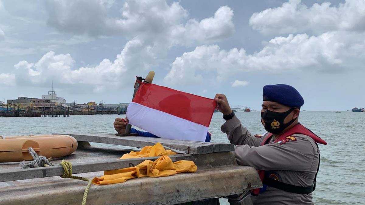 Kasat Polairud Polres Karimun Iptu Binsar Samosir memasang bendera di salah satu pompong nelayan.
