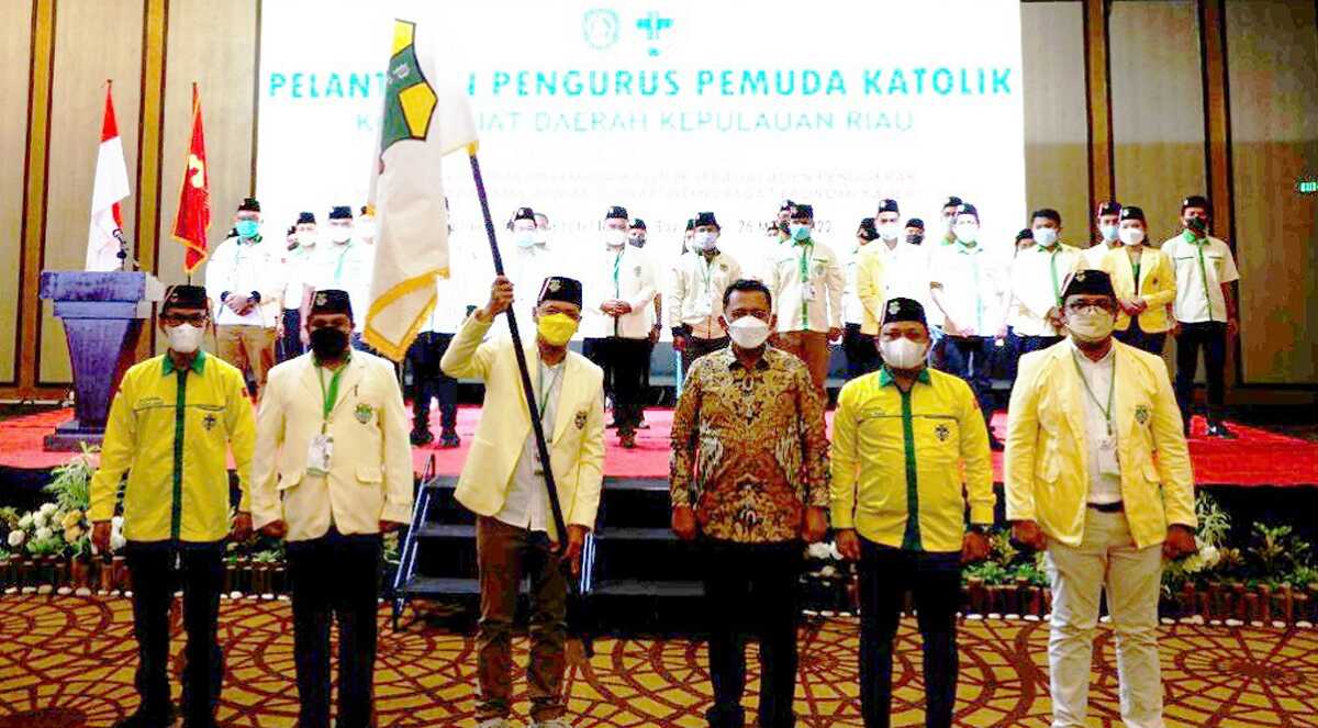 Ketua Pemuda Katolik Komda Kepri Vandarones mengibarkan pataka usai dilantik disaksikan Gubernur Kepri Ansar Ahmad (2 kanan). (foto: istimewa)