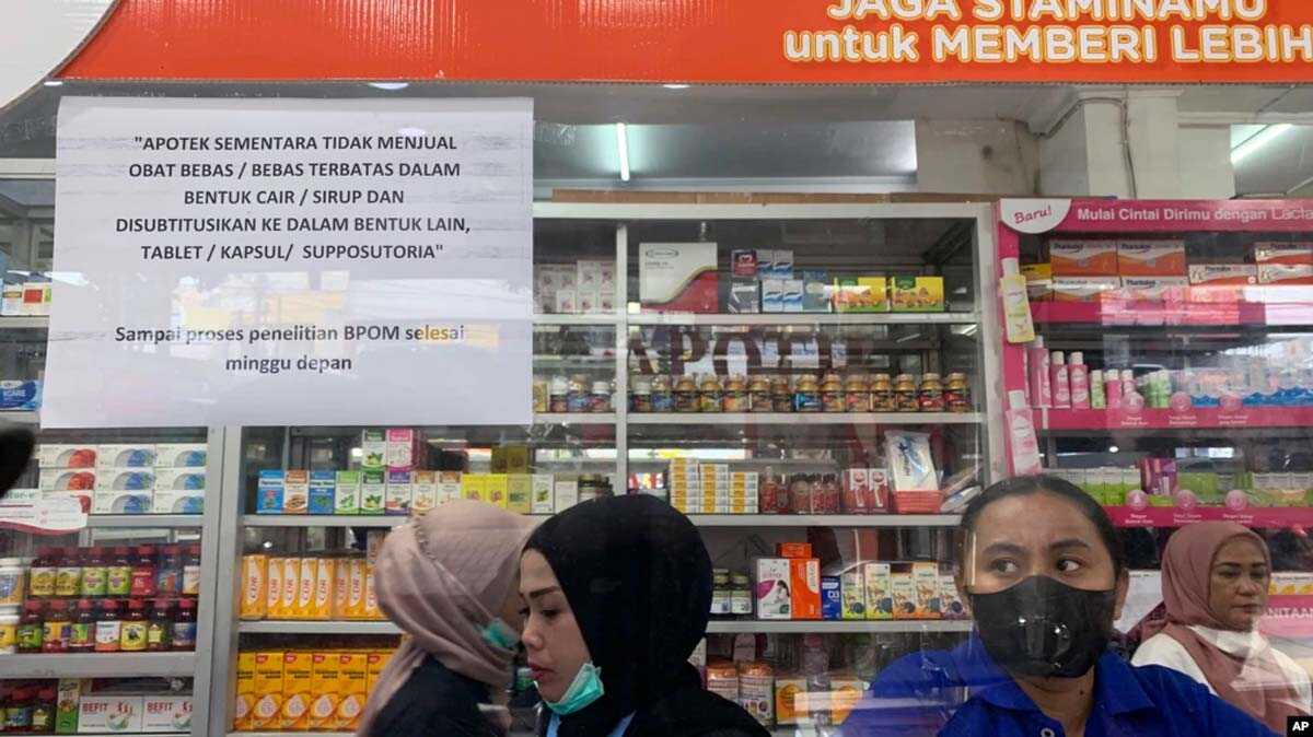 izin produksi dua perusahaan obat Karyawan menunggu pelanggan di loket yang menampilkan pemberitahuan penghentian sementara penjualan sirup obat di apotek di Jakarta, Kamis, 20 Oktober 2022. (AP/Tatan Syuflana)