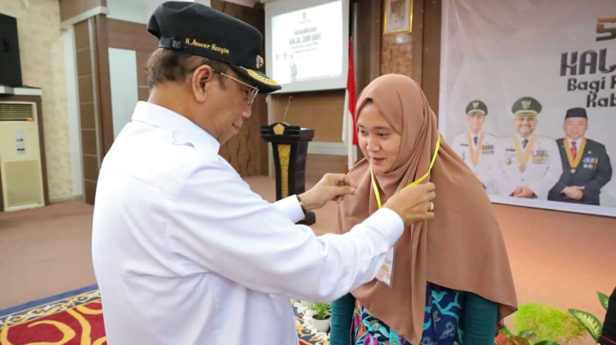 Wakil Bupati Karimun Anwar Hasyim memasang tanda peserta sosialisasi sertifikasi halal dan HAKI di Gedung Nilam Sari, Selasa (13/12/2022). (Dok. Diskominfo Karimun)