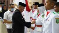Bupati Kepulauan Meranti - Riau H. Muhammad Adil menyematkan lencana sebagai anggota Pasukan Pengibar Bendera Pusaka kepada Nikita Muharamah saat Pengukuhan Paskibraka Kepulauan Meranti, 16 Agustus 2022 lalu. (Foto istimewa)