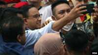 Anies Baswedan (tengah) melakukan swafoto dengan pendukungnya setelah dirinya resmi menyelesaikan tugasnya selama 5 tahun dari 2017 hingga 2022 sebagai gubernur DKI Jakarta pada 16 Oktober tahun ini. (VOA/Indra Yoga)