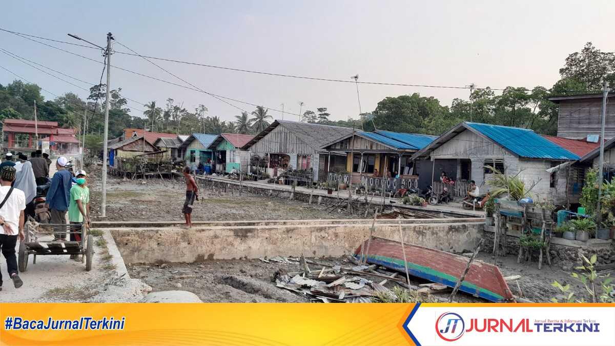 Pemukiman Suku Asli Sejumlah warga melintas di jalan depan pemukiman suku Asli di pesisir, persisnya di pintu masuk pelabuhan Desa Sei Asam, Kecamatan Belat, Kabupaten, Karimun, Kepulauan Riau, Rabu (12/4/2023). Suku Asli merupakan penduduk yang relatif tertinggal, umumnya tinggal di pinggir laut atau daerah pesisir dan berprofesi sebagai nelayan. (JurnalTerkini.id/Rusdi)
