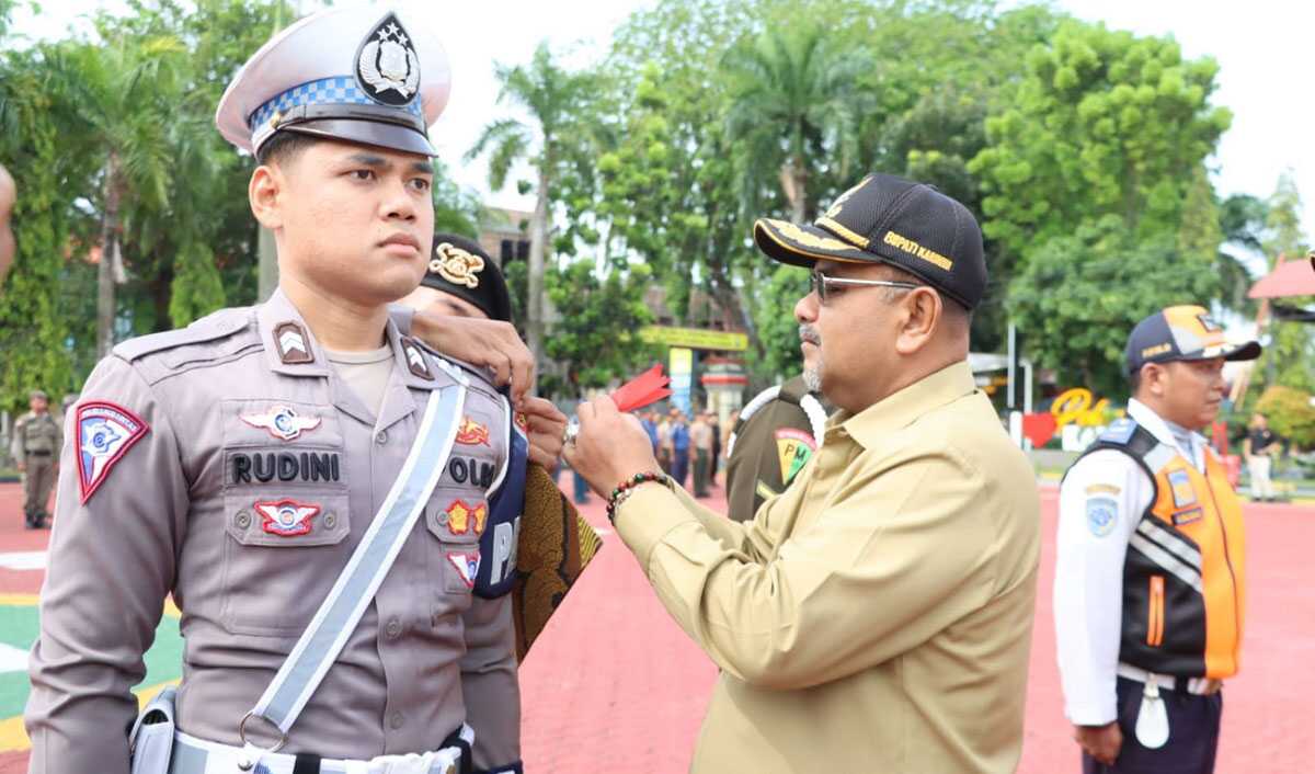 Bupati Karimun Aunur Rafiq menyematkan pita kepada salah satu personel Operasi Ketupat Seligi 2023 dalam apel gelar pasukan di Mapolres Karimun, Senin (17/4/2023). (Dok. Humas Polres Karimun)