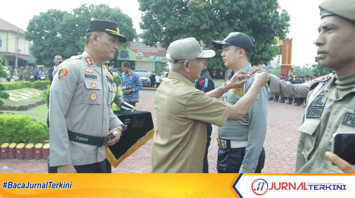 Bupati Asahan H Surya menyematkan pita kepada personel yang terlibat dalam Operasi Ketupat Toba 2023 dalam apel gelar pasukan di Mapolres Asahan, Senin (17/4/2023). (JurnalTerkini.id/Rizki)