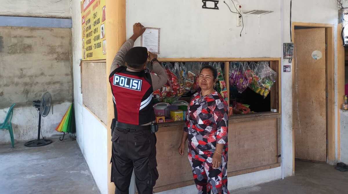 Personel Polres Bintan memasang selebaran atau brosur berisi  larangan membakar hutan dan lahan di sebuah warung, Selasa (9/5/2023). (Dok. Humas Polres Bintan)
