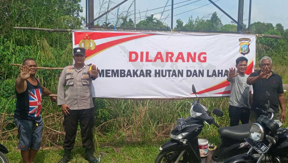 Personel Polres Bintan memasang spanduk larangan membakar hutan dan lahan di sebuah kawasan perkebunan, Selasa (9/5/2023). (Dok. Humas Polres Bintan)