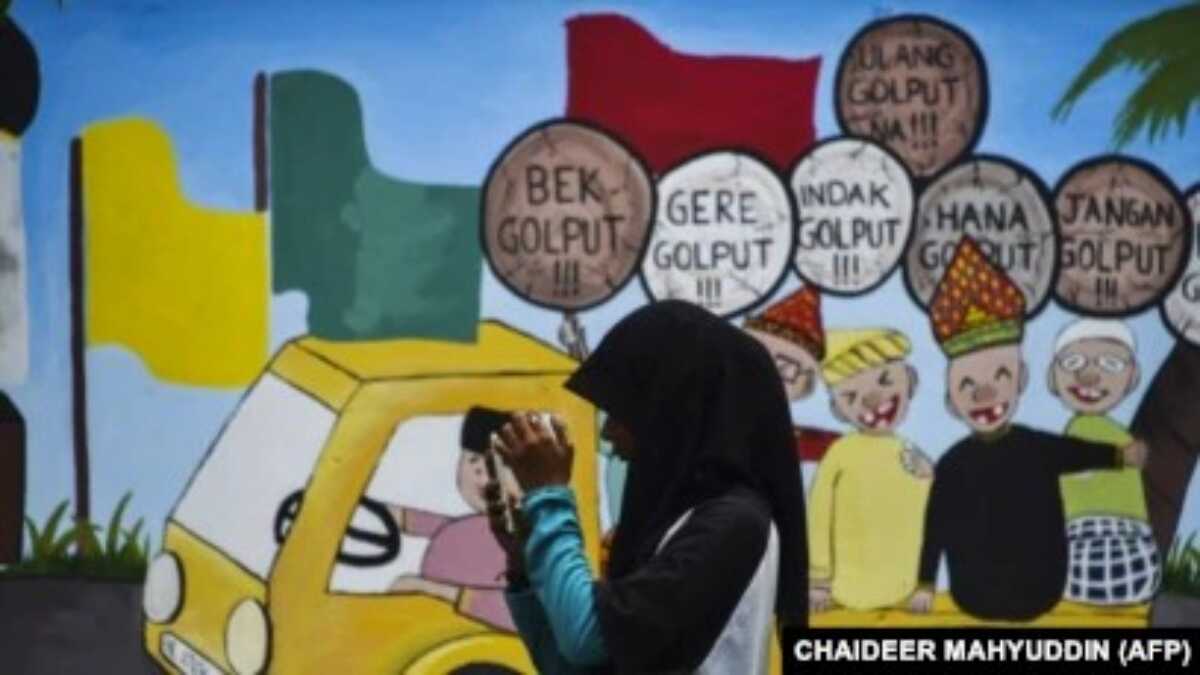 mural pemilu Seorang pemuda menggunakan ponselnya di depan mural kampanye Pemilu 2019, Banda Aceh, 17 Maret 2019. (Foto: AFP/CHAIDEER MAHYUDDIN)