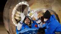 satelit tiongkok Astronaut Liu Yang melambaikan tangannya sesaat setelah ia keluar dari kapsul pesawat ruang angkasa Shenzou-14 yang mendarat di stasiun pendaratan Dongfeng, China, pada 4 Desember 2022. (Foto: China Daily via Reuters)