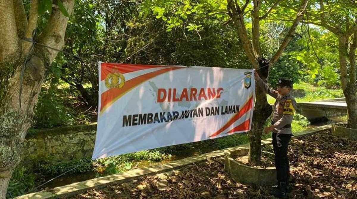 spanduk larangan bakar hutan di karimun Seorang Bhabinkamtibmas memasang spanduk maklumat larangan bakar hutan dan lahan di salah satu lokasi di Tanjung Balai Karimun,, Rabu (17/5/2023). (Dok. Humas Polres Karimun)