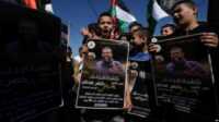 Anak-anak dan remaja Palestina mengibarkan bendera nasional dan memegang poster Khader Adnan, seorang militan Jihad Islam Palestina yang meninggal di penjara Israel setelah mogok makan hampir tiga bulan, di desa Arrabe Tepi Barat, dekat Jenin, Selasa, 2 Mei 2023.