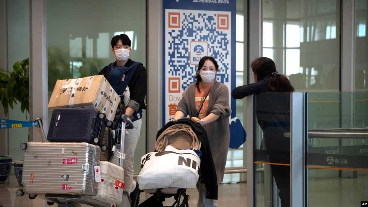 bandara internasional beijing Sejumlah wisatawan memakai masker di area kedatangan Bandara Internasional Beijing pada 26 April 2023. (Foto: AP/Mark Schiefelbein)