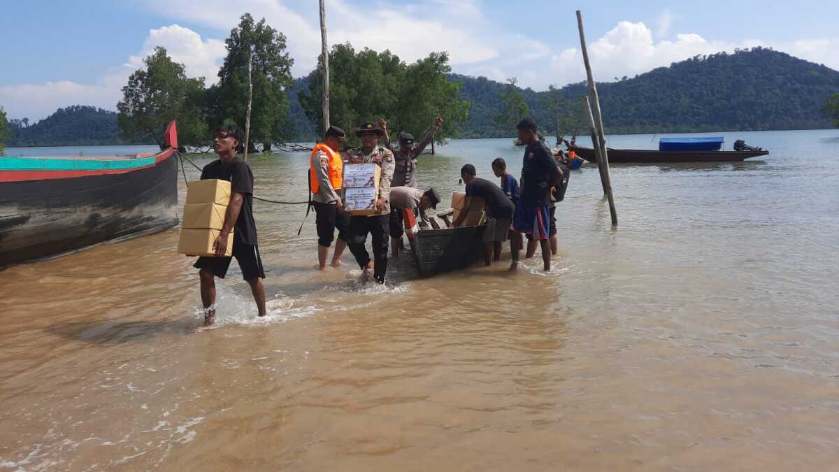 Warga sukus asli membantu mengangkut paket bansos yang dibawa Polsek Tebing ke pemukiman mereka di pulau terdepan, Pulau Karimun Anak, Jumat (23/6/2023). (Dok. Humas Polres Karimun)