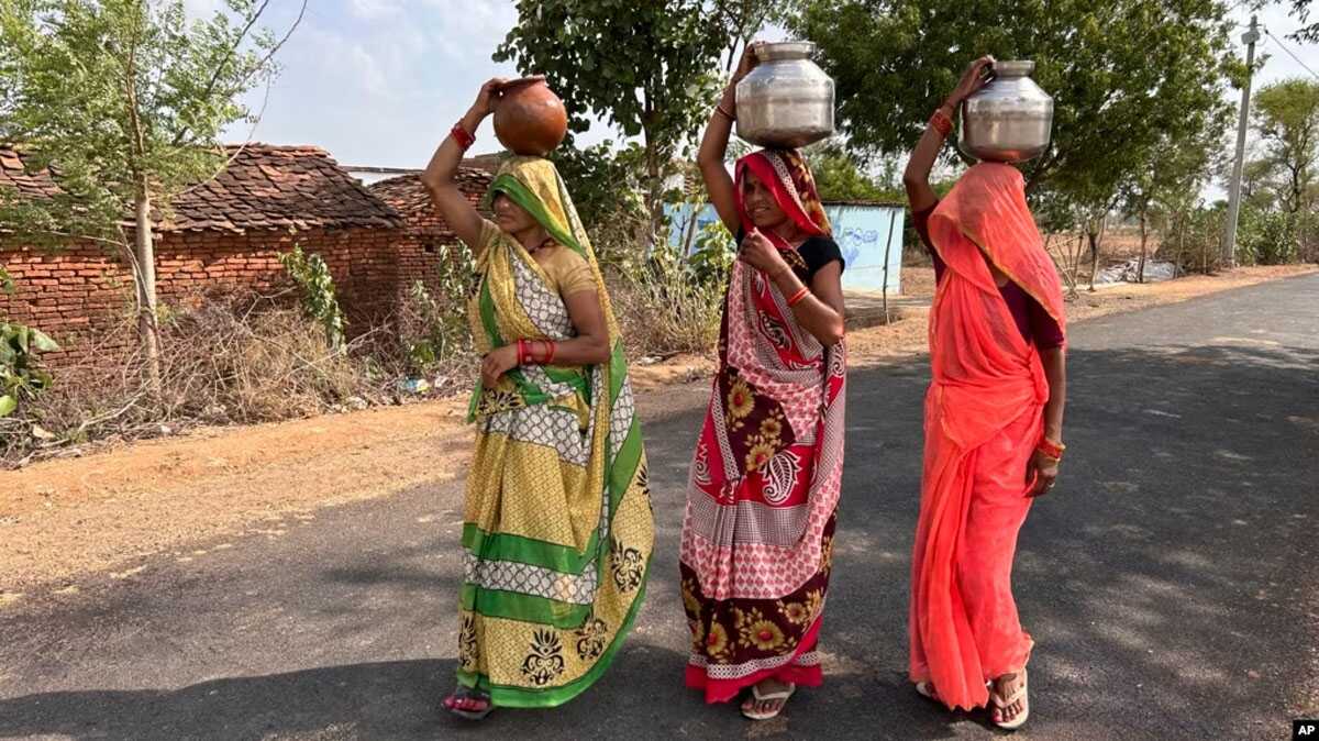 gelombang panas di india Tiga wanita berjalan sambil membawa kendi berisi air minum pada suatu sore musim panas yang terik di Lalitpur, negara bagian Uttar Pradesh, India, Sabtu, 17 Juni 2023. (AP/Rajesh Kumar Singh)