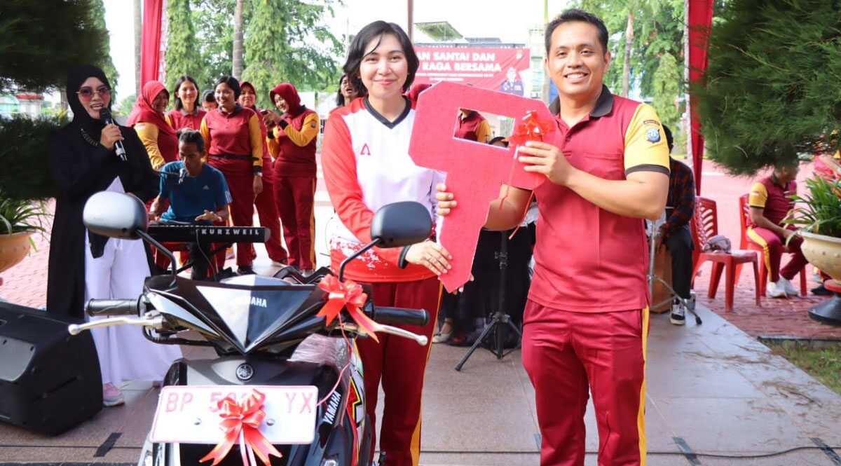 Wakapolres Karimun Kompol Petra C K Tumengkol menyerahkan hadiah utama sepeda motor kepada pemenang hadiah doorprize acara jalan santai dan olahraga bersama menyambut Hari Bhyangkara ke-77 di lapangan Polres. Sabtu (24/6/2023) pagi. (Dok. Humas Polres Karimun)