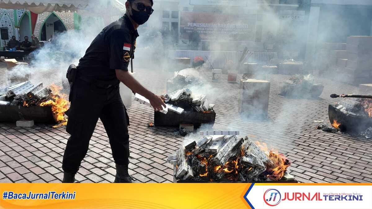 Seorang petugas Kejari Karimun melempar satu slop rokok untuk dibakar dalam pemusnahan barang bukti perkara berkekuatan hukum tetap di halaman Kantor Kejari Karimun, Kamis (22/6/2023). (JurnalTerkini.id/rusdi)