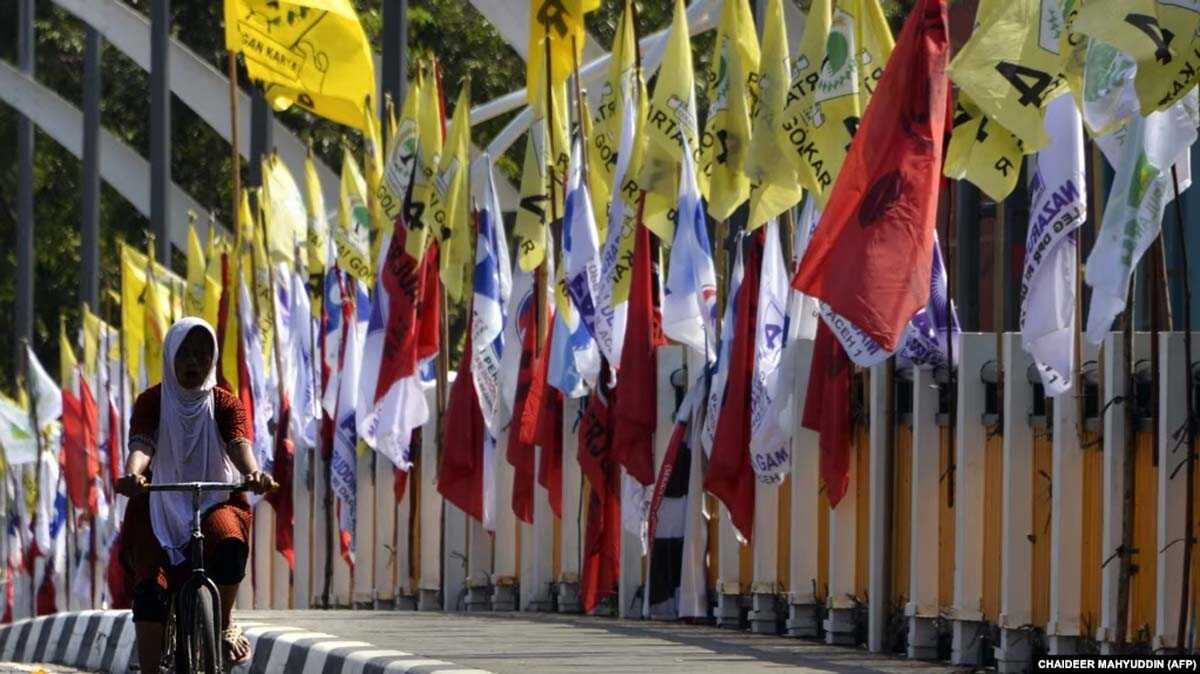 bendera partai politik Seorang perempuan bersepeda melewati bendera partai politik jelang Pemilu 2019 di Banda Aceh, 23 Maret 2019. (Foto: AFP/CHAIDEER MAHYUDDIN)