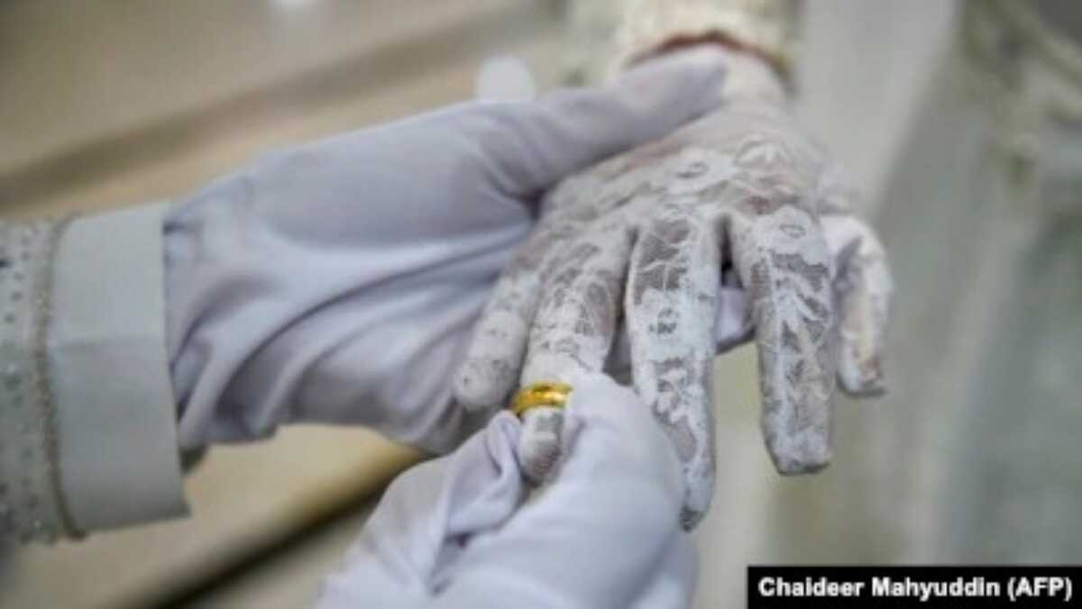 Pengantin pria menyematkan cincin di tangan pengantin wanita dalam akad nikah di sebuah masjid di Banda Aceh, 3 Juni 2020. (Foto: Chaideer Mahyudin/AFP)
