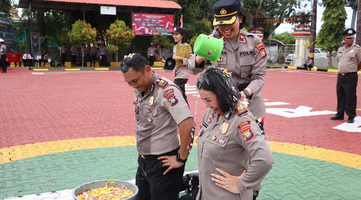 Wakapolres Karimun Kompol Petra C K Tumengkol menyiramkan air kembang kepada Kasat Reskrim Gidion Karo Sekali dan Wakapolsek Balai Karimun Kumala Enggar Anjarani dalam upacara kenaikan pangkat di Mapolres Karimun, Sabtu (1/7/2023). Keduanya naik pangkat dari Inspektur Polisi Satu (Iptu) ke Ajun Komisaris Polisi (AKP). (Dok. Humas Polres Karimun)