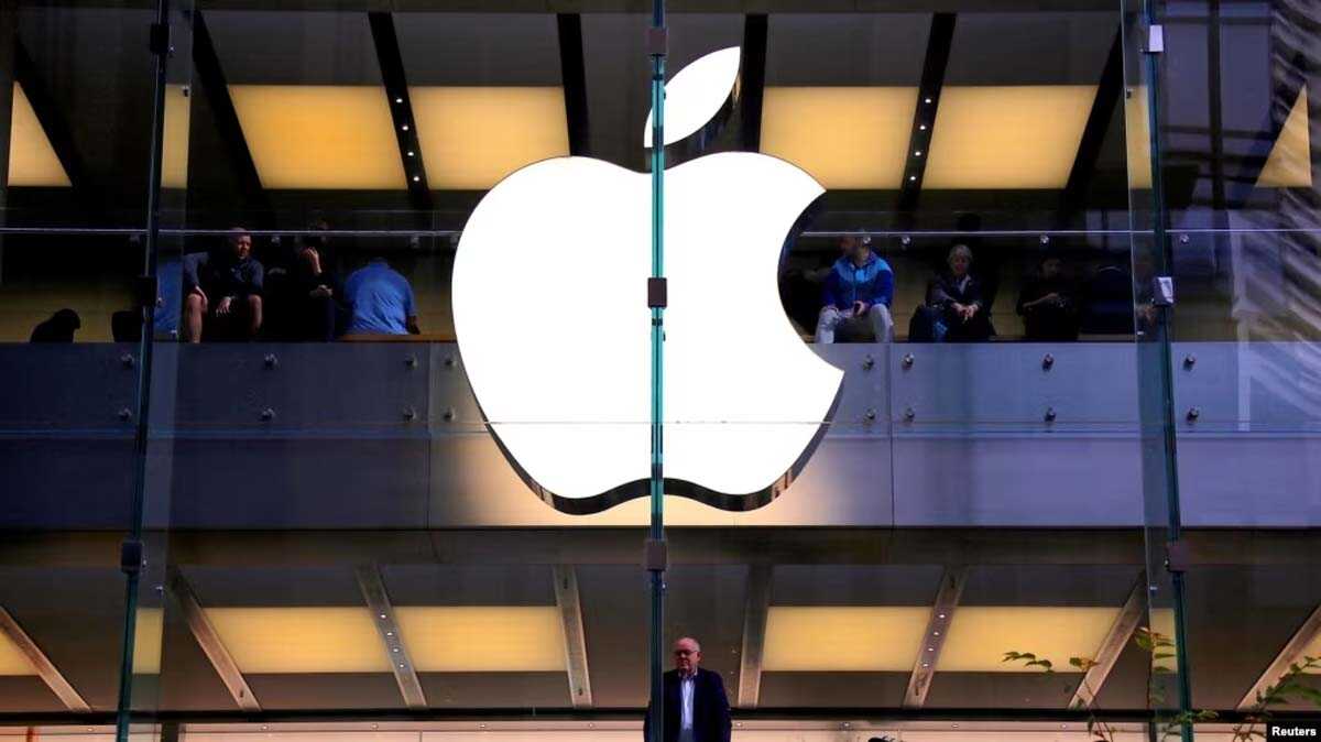 perusahaan apple Seorang pelanggan berdiri di bawah logo Apple yang menyala saat dia melihat ke luar jendela toko Apple yang terletak di pusat kota Sydney. (Foto: Reuters)