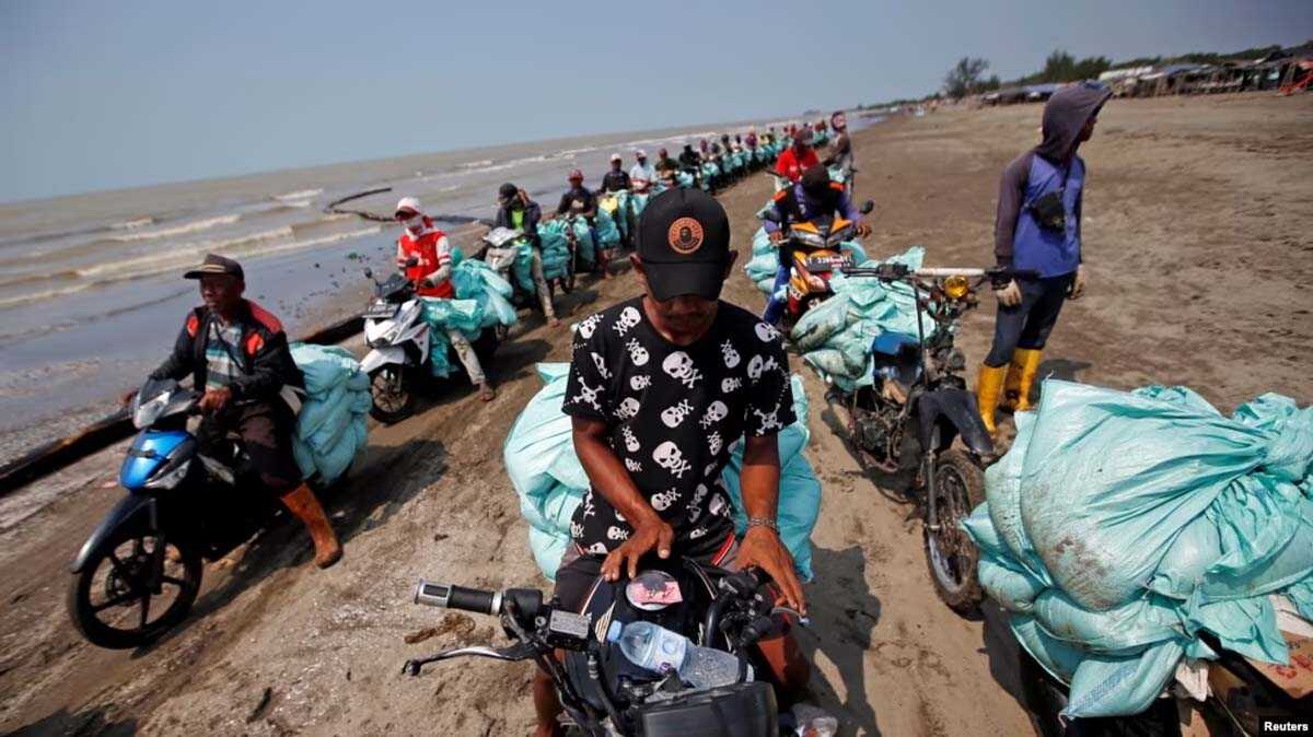 pesisir pantai di karawang Sejumlah warga tampak menggangkut kantor berisi pasir pantai yang tercemar oleh oli di pesisir pantai di Karawang, Jawa Barat, pada 2 Agustus 2019. (Foto: Reuters/Willy Kurniawan)