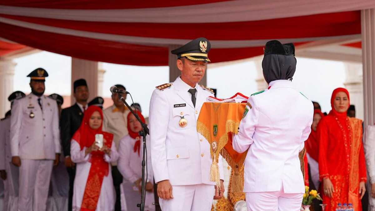 Bupati Rohil Afrizal Sintong menyerahkan bendera merah putih kepada anggota Paskibara (Dok. Humas Pemkab Rohil)