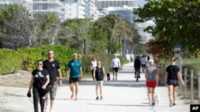 jalan jalan kurangi risiko kematian ILUSTRASI - Orang-orang berjalan-jalan dengan anjing mereka dan berolahraga di jalan yang padat di sepanjang sisi pantai, Sabtu, 21 Maret 2020, di Surfside, Florida. (AP/Wilfredo Lee)