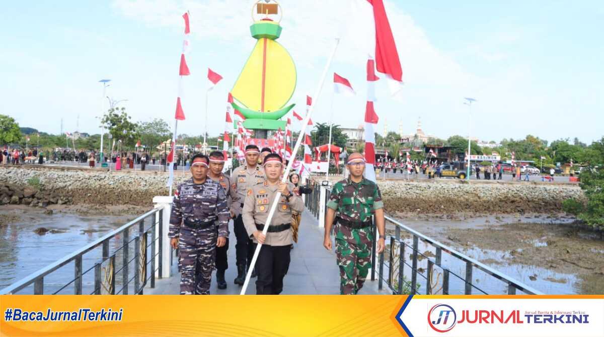 Kapolres Karimun AKBP Ryky W Muharram (tengah), Dandim 0317/TBK Letkol Inf Budianto Hamdani Damanik (kanan) oleh Pasi Ops Lanal Tbk membawa bendera untuk ditancapkan di ujung dermaga landmark Karimun dalam kirab kebangsaan merah puti di Coastal Area, Tanjung Balai Karimun, Selasa (15/8/2023). (Dok. Humas Polres Karimun)