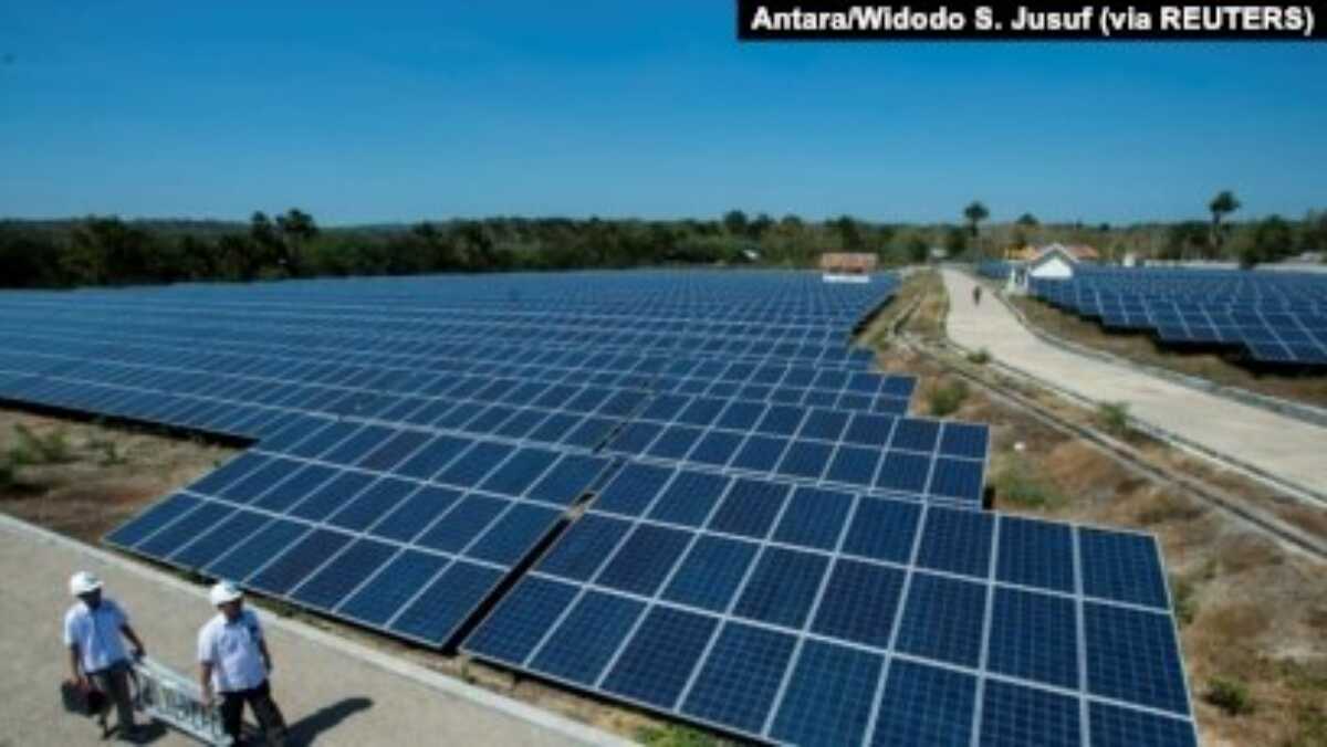 panel tenaga surya Dua petugas Perusahaan Listrik Negara (PLN) melintasi panel sel surya di pembangkit listrik tenaga surya terbesar di Desa Oelpuah, Kupang, 20 Juli 2017. (Foto: Antara/Widodo S. Jusuf via Reuters)