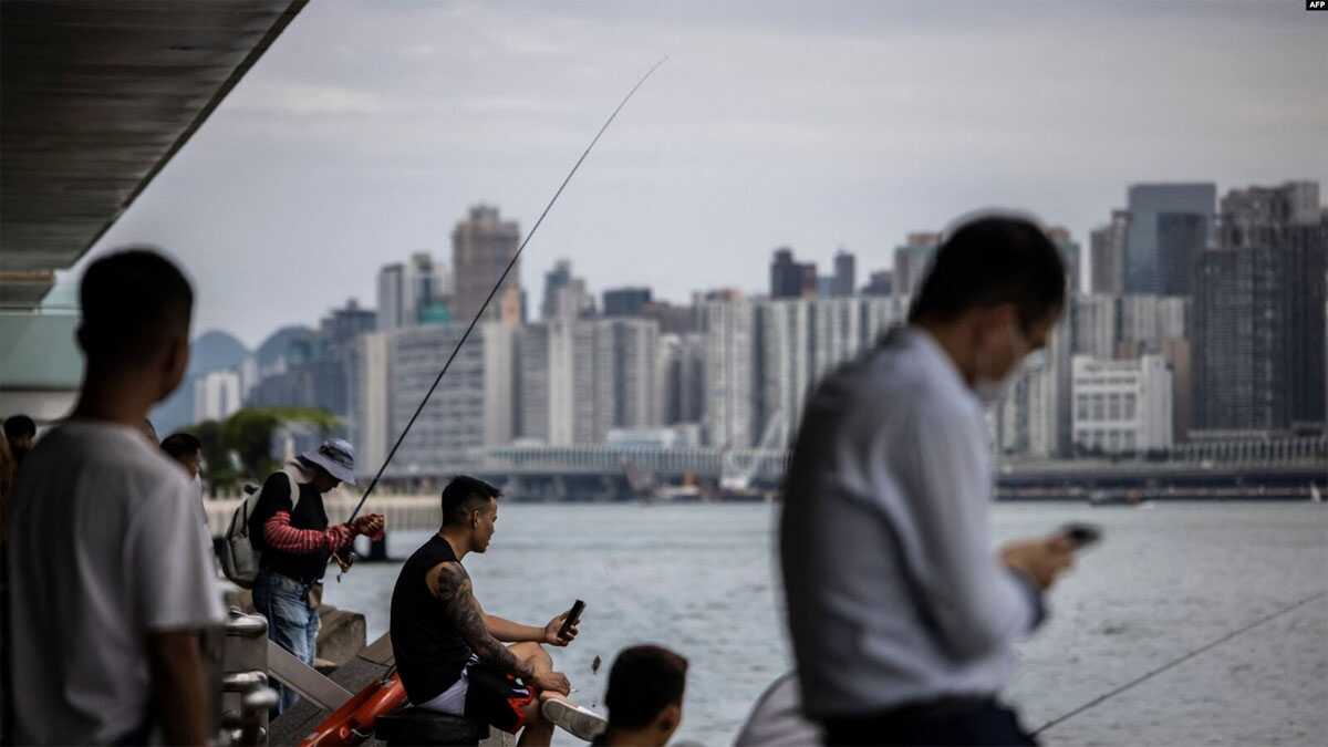 pelabuhan victoria hong kong Orang-orang duduk di sepanjang kawasan pejalan kaki di sebelah pelabuhan Victoria di Hong Kong pada 31 Agustus 2023, sehari sebelum datangnya Topan Saola. (ISAAC LAWRENCE/AFP)