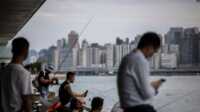 pelabuhan victoria hong kong Orang-orang duduk di sepanjang kawasan pejalan kaki di sebelah pelabuhan Victoria di Hong Kong pada 31 Agustus 2023, sehari sebelum datangnya Topan Saola. (ISAAC LAWRENCE/AFP)