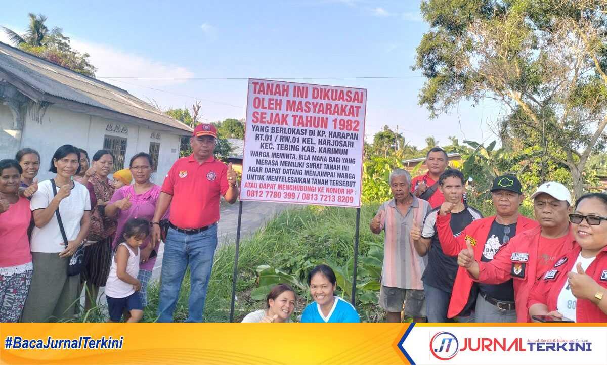 Warga Kampung Harapan, RT 001/RW 001 Kelurahan Harjosari, Kecamatan Tebing, Kabupaten Karimun berpose di samping plang tanah yang mereka kuasai. (JurnalTerkini.id.Jansen M Silalahi)