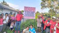 Warga Kampung Harapan, RT 001/RW 001 Kelurahan Harjosari, Kecamatan Tebing, Kabupaten Karimun berpose di samping plang tanah yang mereka kuasai. (JurnalTerkini.id.Jansen M Silalahi)