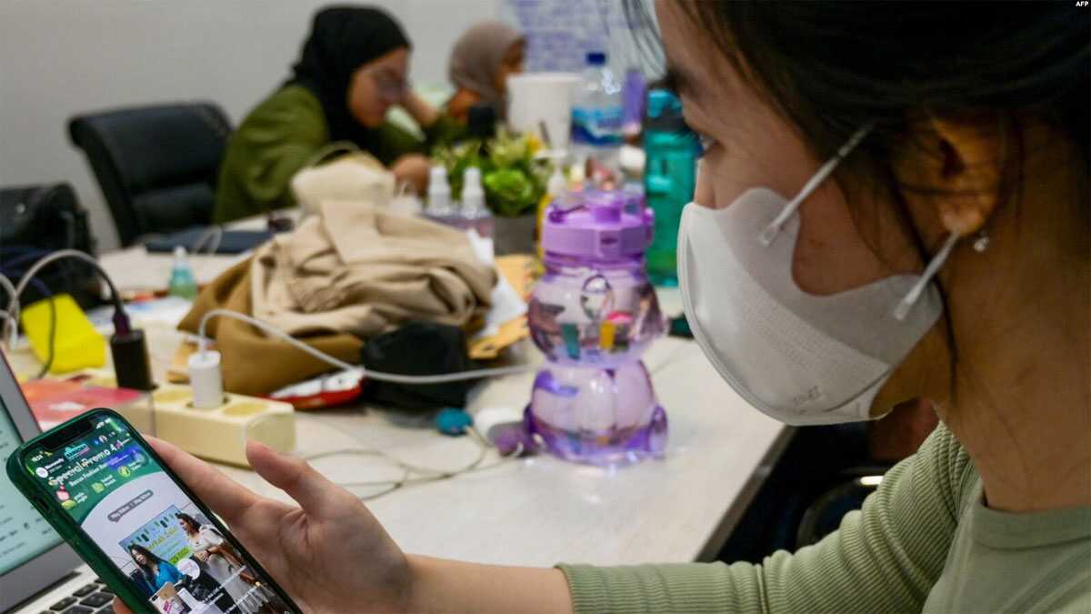 Seorang konsumen sedang memperhatikan live-streaming di TikTok oleh penjual yang menawarkan barangnya, di Jakarta, 4 April 2023. (Foto: Bay Ismoyo/AFP)