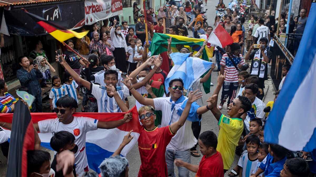 Indonesia ingin tuan rumah piala dunia Penggemar sepak bola mengibarkan bendera negara peserta saat parade jelang kick-off Piala Dunia FIFA Qatar, di Desa Pambusuang, Sulawesi Barat, Minggu, 20 November 2022. (Foto: AP)