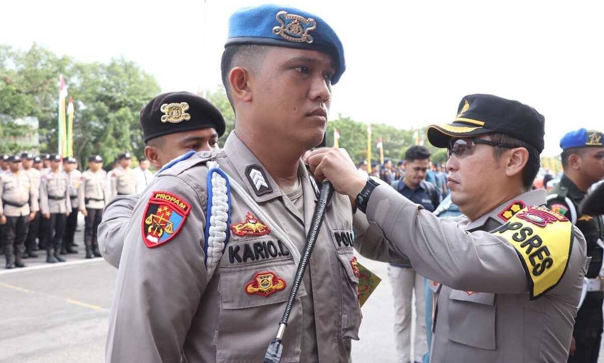 Kapolres Karimun AKBP Ryky W Muharram menyematkan pita kepada personel yang terlibat dalam Operasi Mantap Brata Seligi 2023-2024 dalam apel gelar pasukan di Coastal Area, Tanjung Balai Karimun, Selasa (17/10/2023). (Dok Humas Polres Karimun)