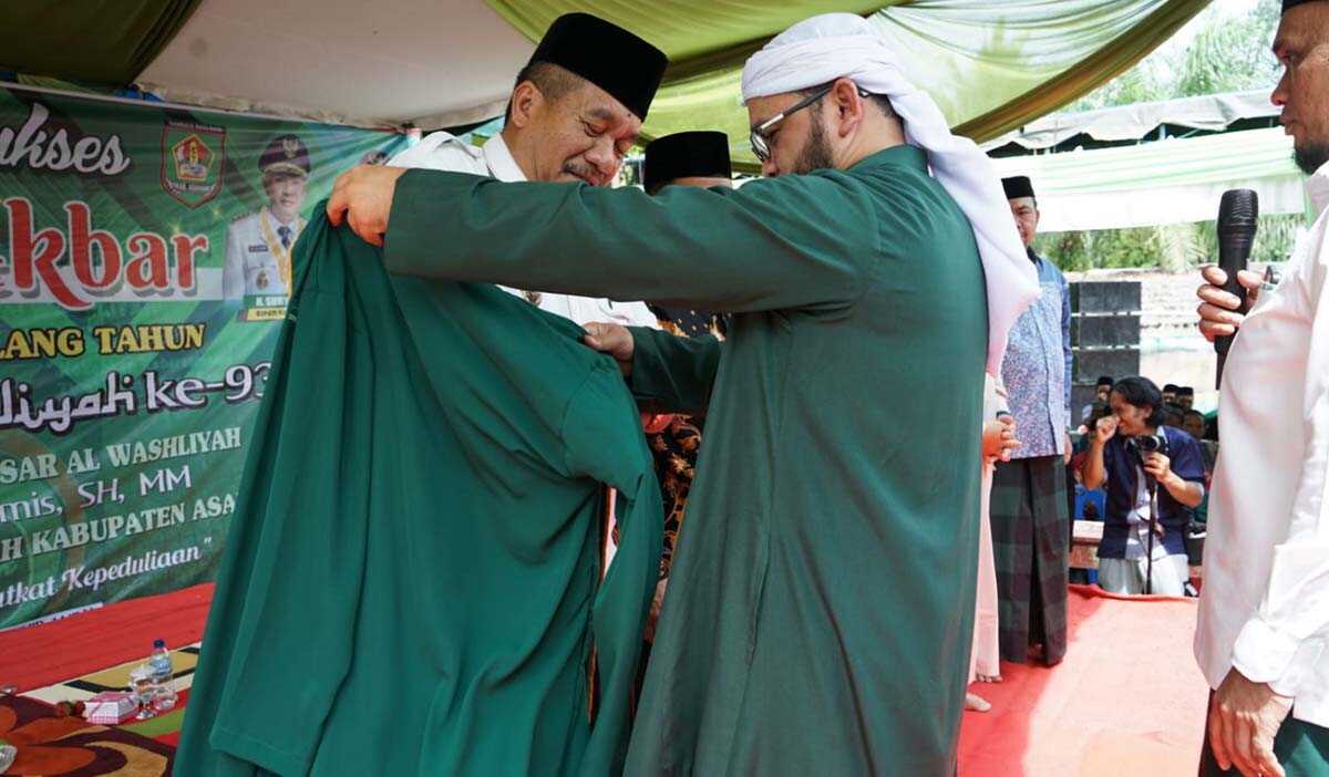 Tabligh akbar jamiyatul washliyah asahan Wakil Bupati menerima pemasangan jubah Asatidz Al Washliyah dari Ketua PW Al Washliyah Sumut Dr H Dedi Iskandar Batu Bara di sela tabligh akbar HUT Jam'iyatul Washliyah ke-93 di MTs Al Washliyah 63 Desa Punggulan Kecamatan Air Joman, Rabu (25/10/2023). (Dok Diskominfo Asahan)