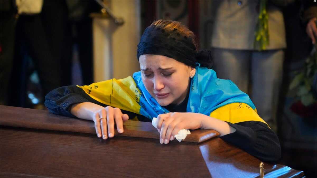 Seorang janda menangis di peti mati tentara sukarelawan Oleksandr Makhov, 36 tahun, seorang jurnalis terkenal Ukraina, yang dibunuh oleh pasukan Rusia, di katedral St Michael di Kyiv, Ukraina, Senin, 9 Mei 2022. (Foto: AP)