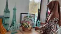 miniatur kaca ekraf umkm karimun Petugas Rumah Kreatif BUMN di Coastal Area, Tanjung Balai Karimun, Minggu (12/11/2023) mengamati miniatur gedung atau bangunan dari limbah atau potongan-potongan kaca yang dipajang di pusat pengembangan dan promosi itu. (JurnalTerkini.id/jansen)