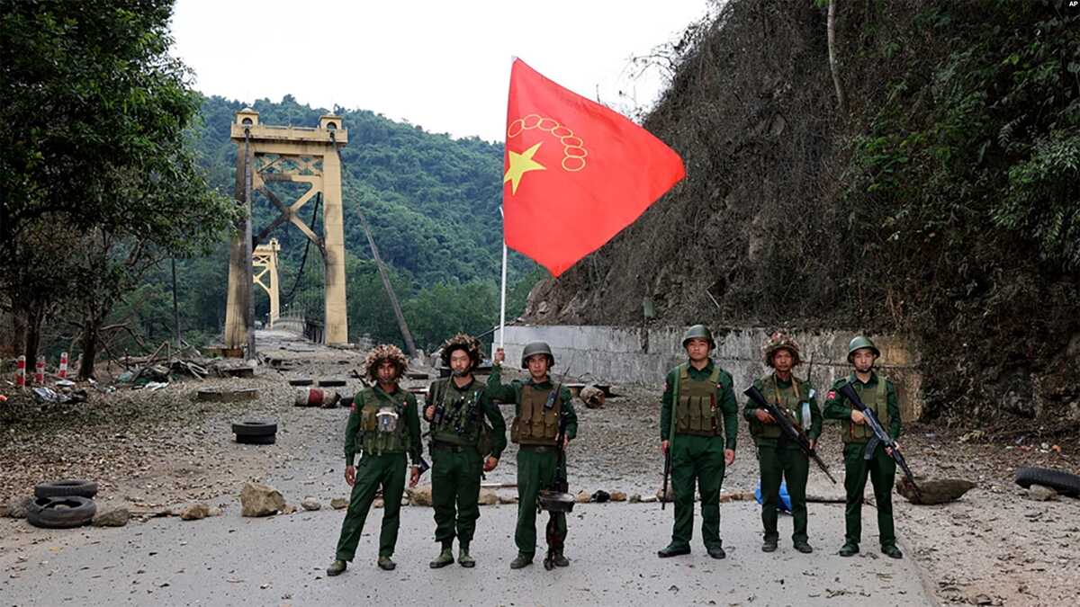 FILE - Anggota Tentara Aliansi Demokratik Nasional Myanmar berpose dengan bendera kelompok tersebut di depan jembatan Kunlong di negara bagian Shan, Myanmar, 12 November 2023.
