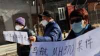 tragedi malaysia airlines Anggota keluarga membawa spanduk saat berbicara kepada media setelah sidang pengadilan tentang kompensasi bagi mereka yang kehilangan orang yang mereka cintai dalam penerbangan Malaysia Airlines MH370 di Beijing, Tiongkok, 27 November 2023. (REUTERS/Florence Lo)