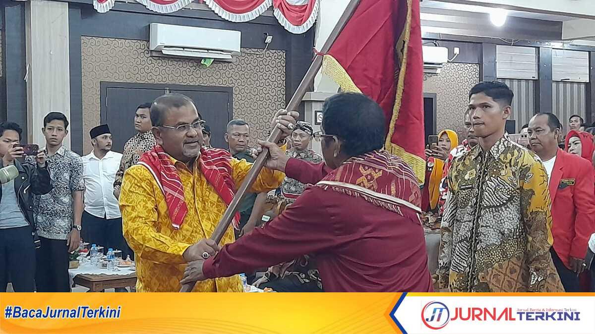 Bupati Karimun Aunur Rafiq menyerahkan pataka kepada Vandarones Purba yang dilantik sebagai Ketua Perkumpulan Karo Merga Silima Kabupaten Karimun (PKMSKK) pEriode 2023-2028 di Gedung Nasional. Rabu (29/11/2023) malam. (JurnalTerkini.id/jansen)